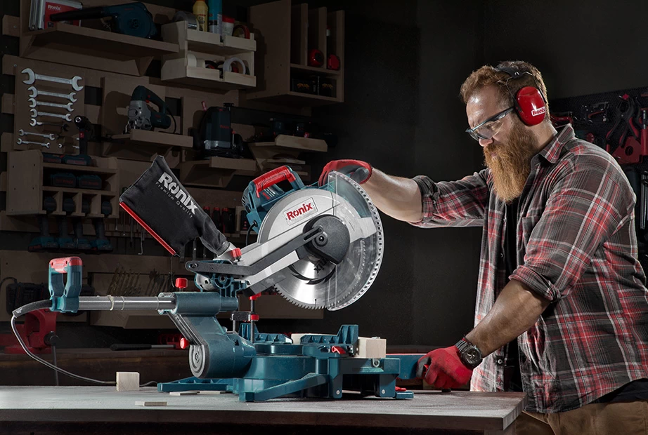  A man operating a Ronix miter saw with its blade cover engaged