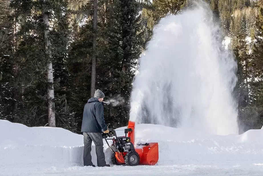 A snow blower is being used to clear a driveway