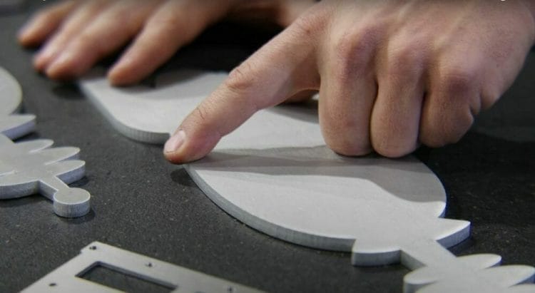 Screenshot from the video showing Jake pointing to a sharp edge on a part post sheet metal deburring.